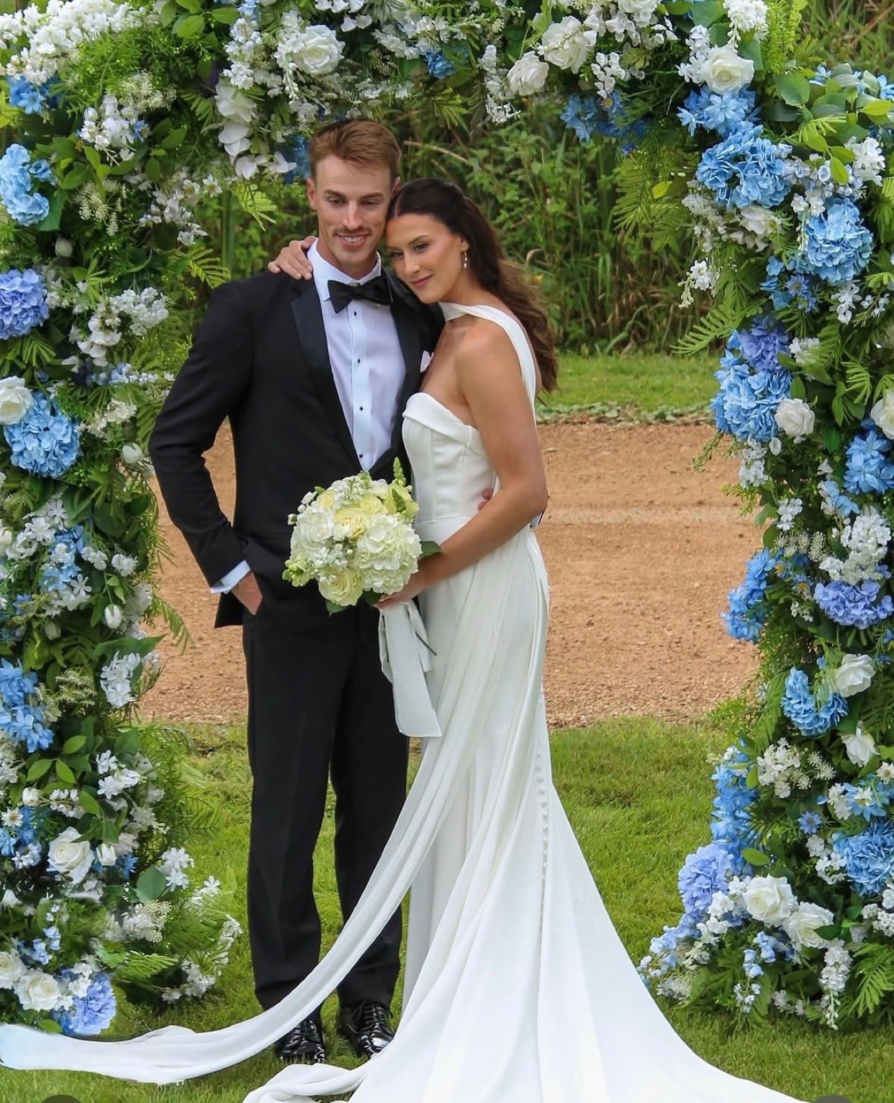 Bride and groom under a floral arch on their wedding day